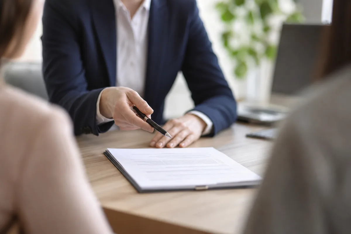 Conseiller présentant un contrat de prévoyance à un couple dans un bureau